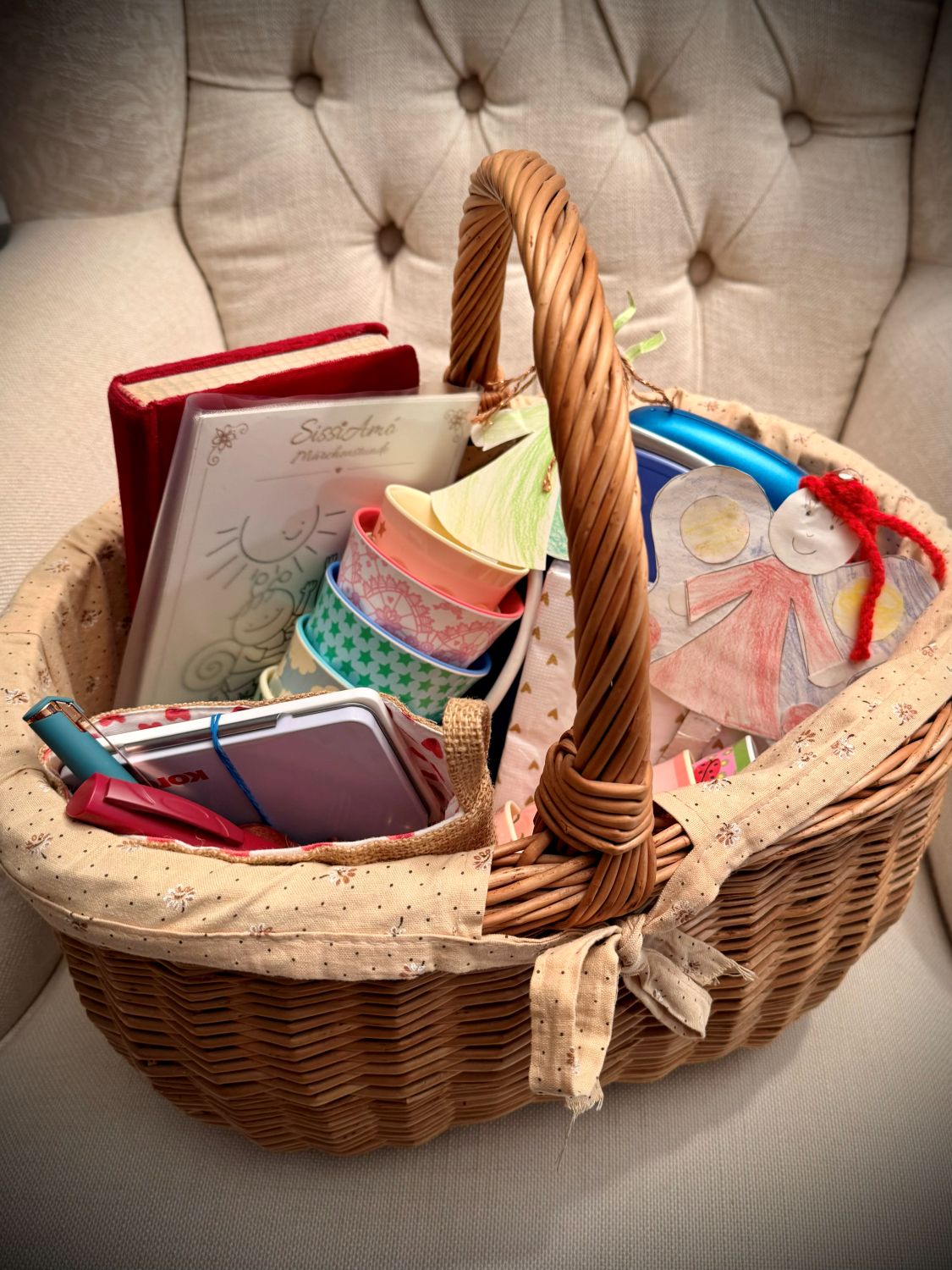 Gepackter Korb mit Büchern, Märchenkarten, bunten Bechern und Papierfiguren